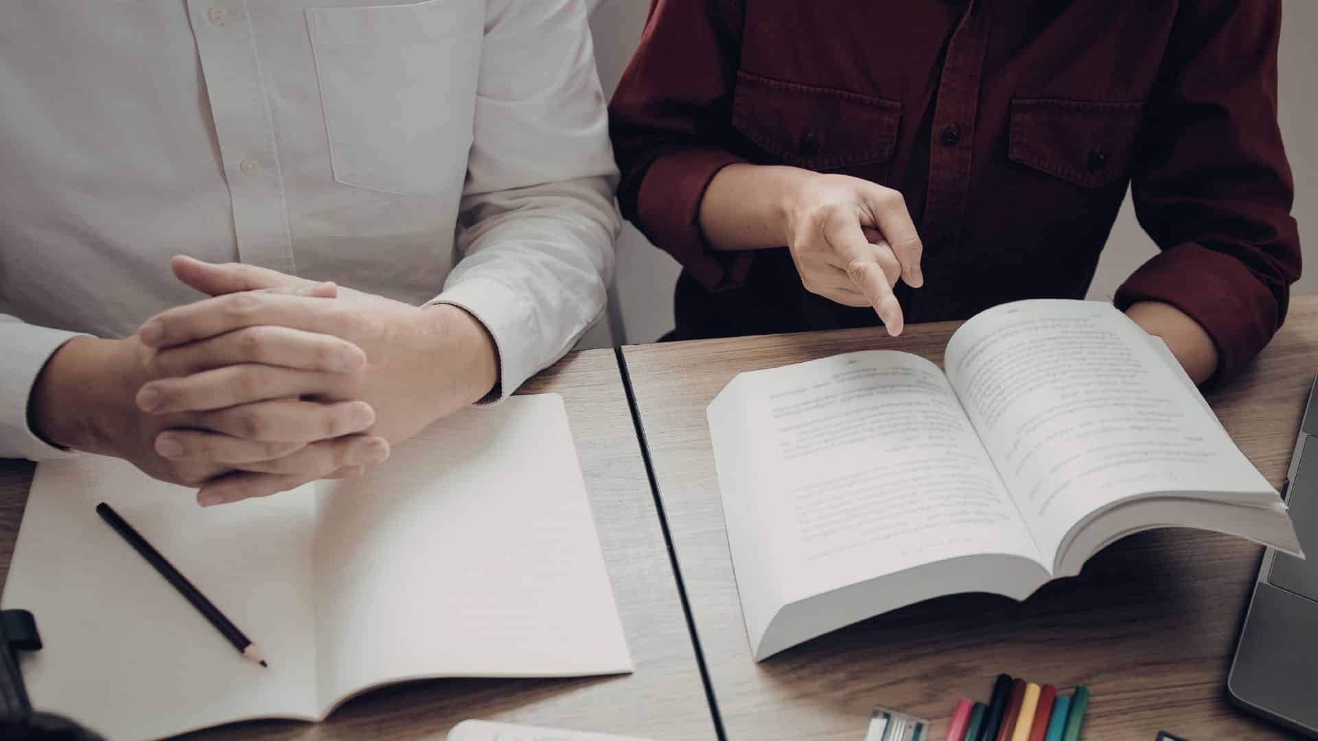 Students reviewing a book and notes together, highlighting academic strengths like critical thinking, collaboration, and focused learning skills