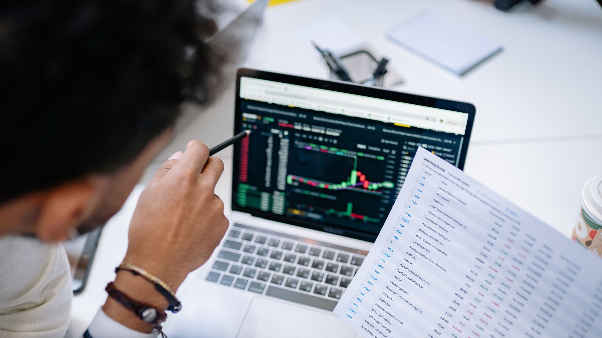 Trader analyzing options chart on laptop with data sheet, representing what open interest means in options, market liquidity, and trading activity