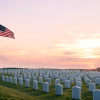 American flag at half-staff beside military graves at sunrise showing a quiet and respectful Memorial Day scene
