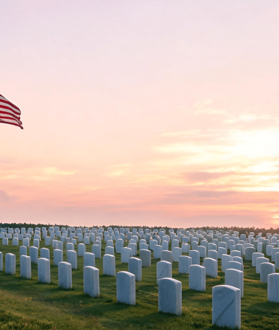 American flag at half-staff beside military graves at sunrise showing a quiet and respectful Memorial Day scene