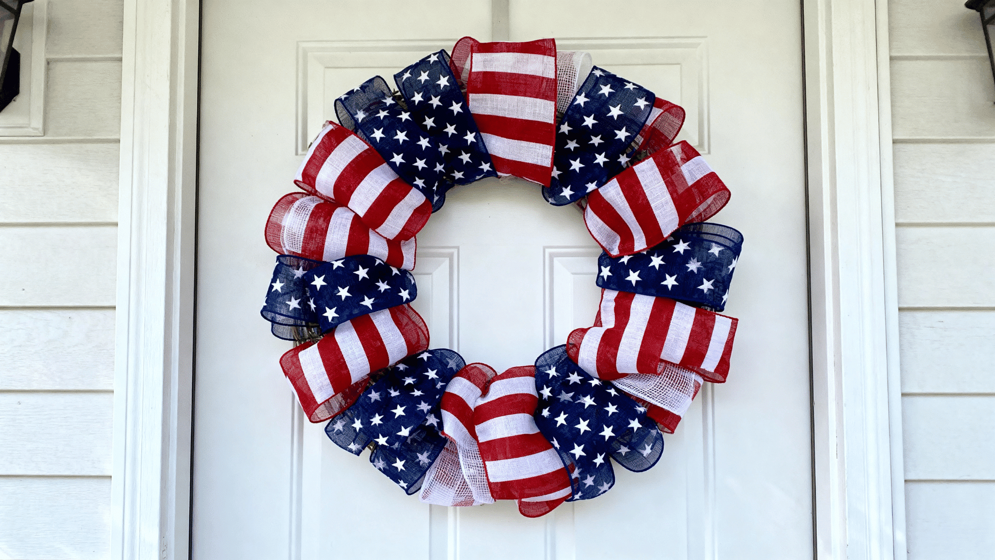 American flag wreath with red white blue ribbons on a clean front door