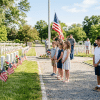Children observing Memorial Day with flags in a calm outdoor setting, showing respect and remembrance