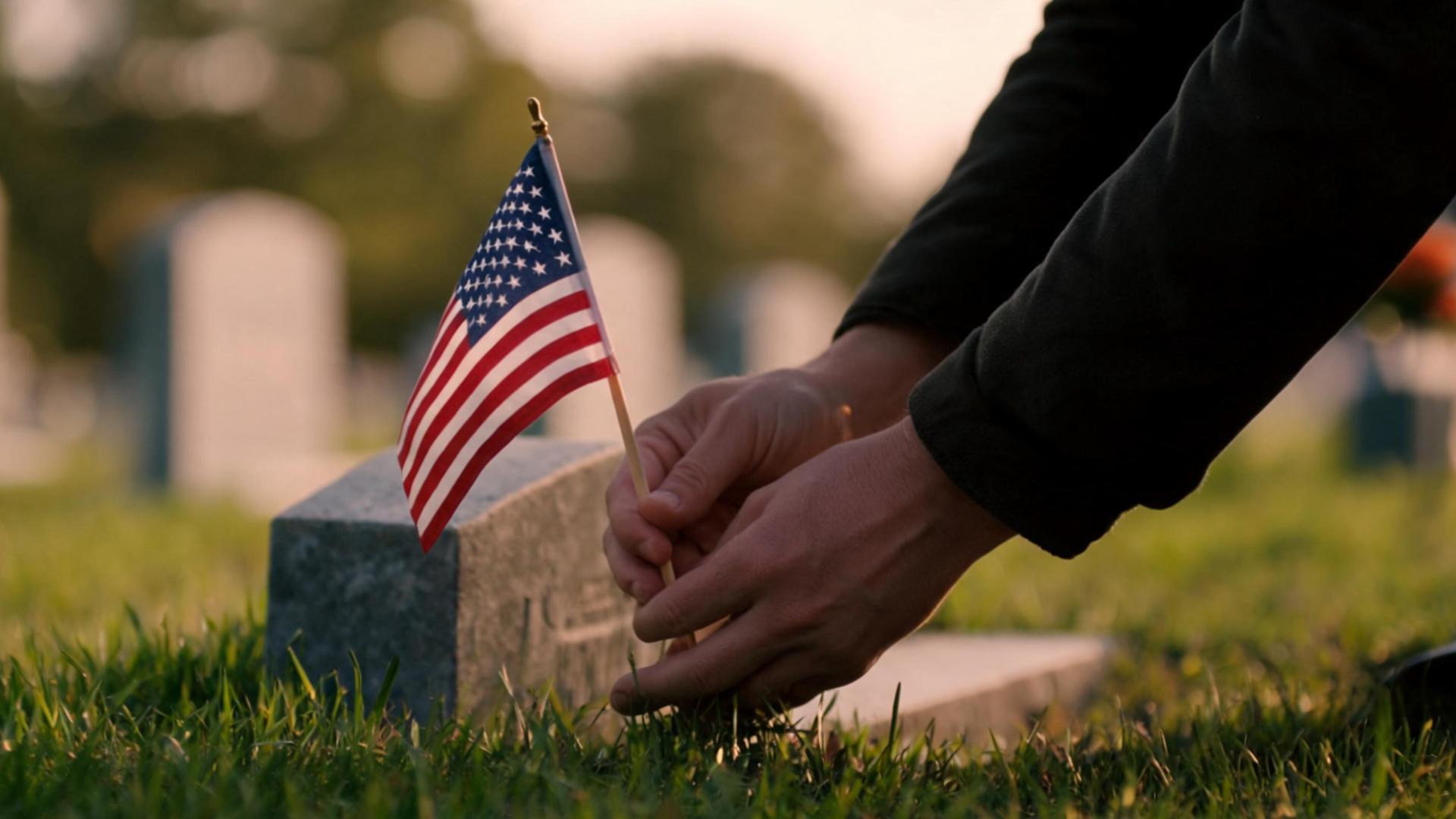 Hands placing small American flags on graves in a cemetery as a tribute to fallen soldiers on Memorial Day