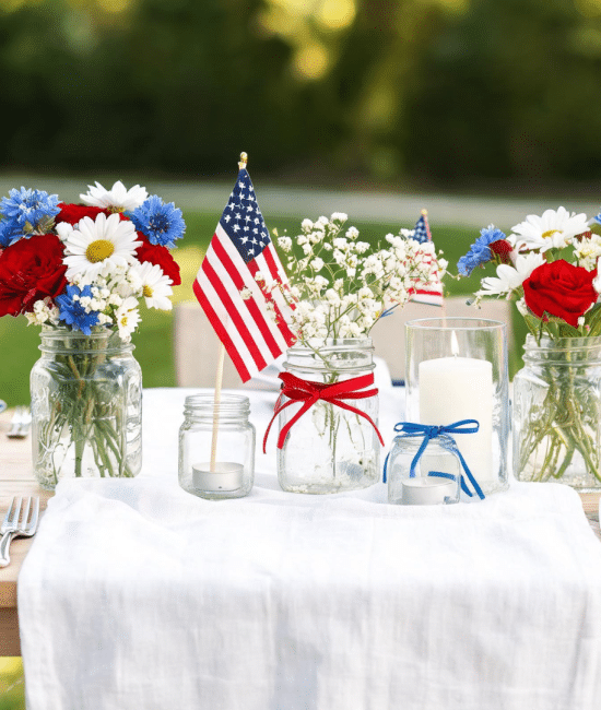 Memorial Day table with patriotic centerpieces, including flowers, candles, and flags in red, white, and blue theme
