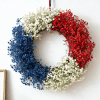 _Red, white, and blue floral wreath hanging on wall with simple home decor background