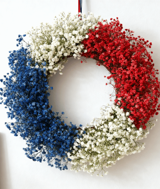 _Red, white, and blue floral wreath hanging on wall with simple home decor background