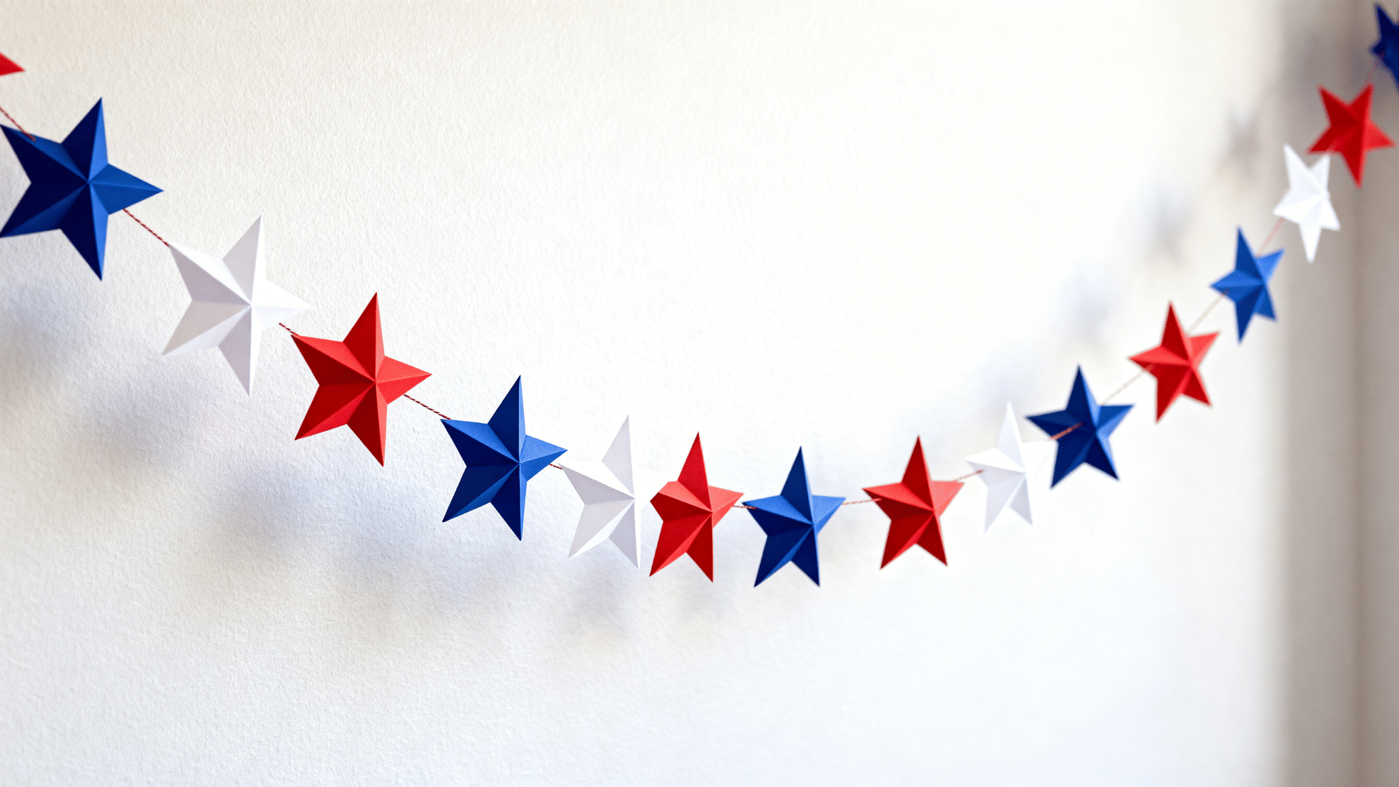 Red white blue star garland hanging on plain wall