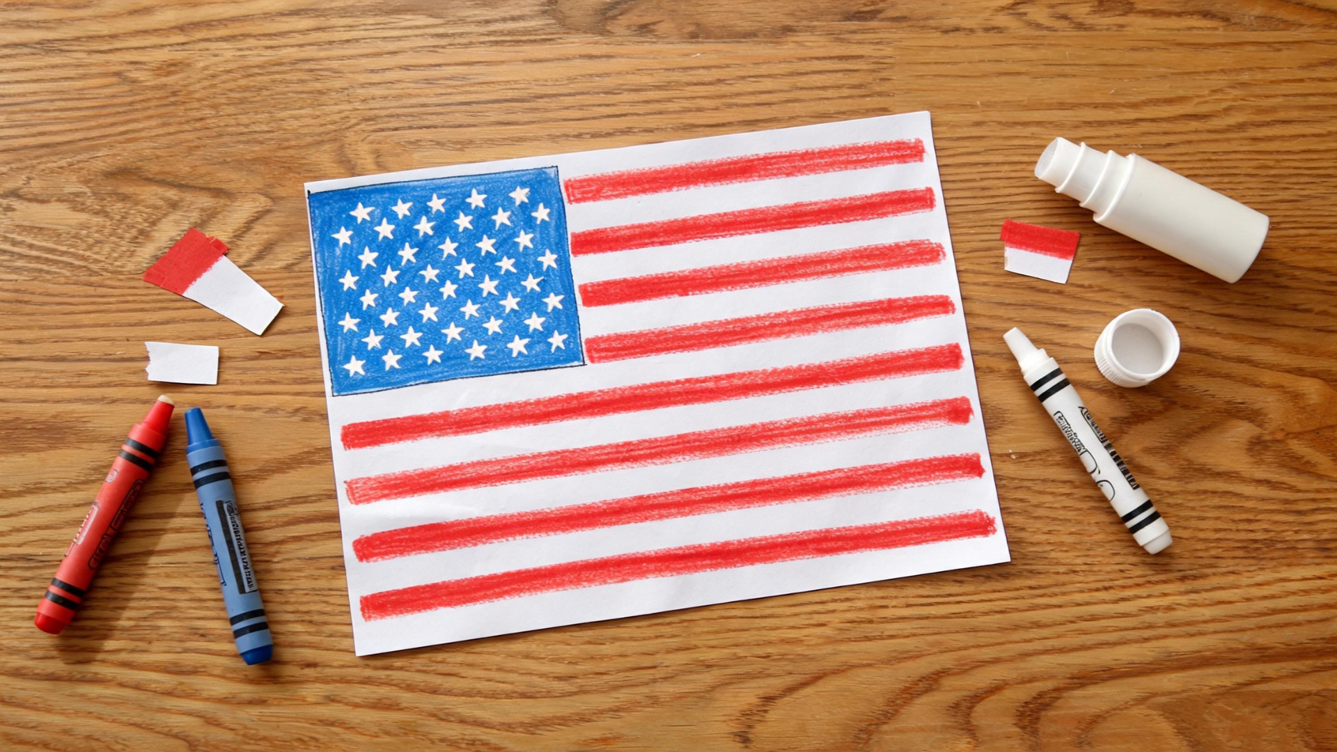 Simple American flag craft made with paper, crayons, and glue placed on a wooden table