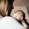 Woman holding newborn baby close in softly lit room