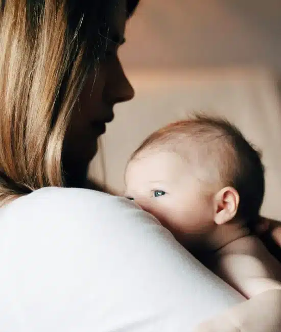 Woman holding newborn baby close in softly lit room