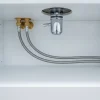 Under-sink plumbing with metal pipes and valves in a white cabinet