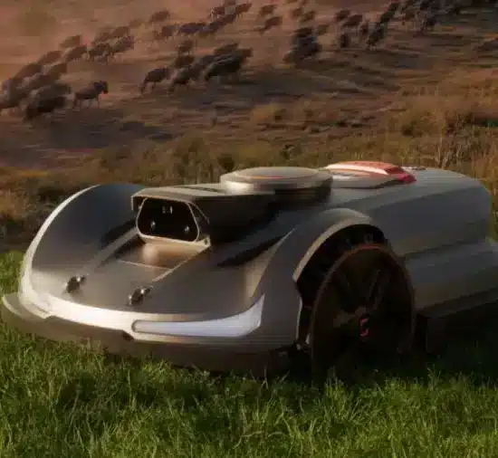 Robotic lawn mower on grassy field with herd of wildebeests in the background