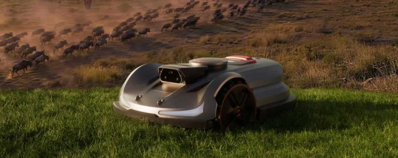 Robotic lawn mower on grassy field with herd of wildebeests in the background
