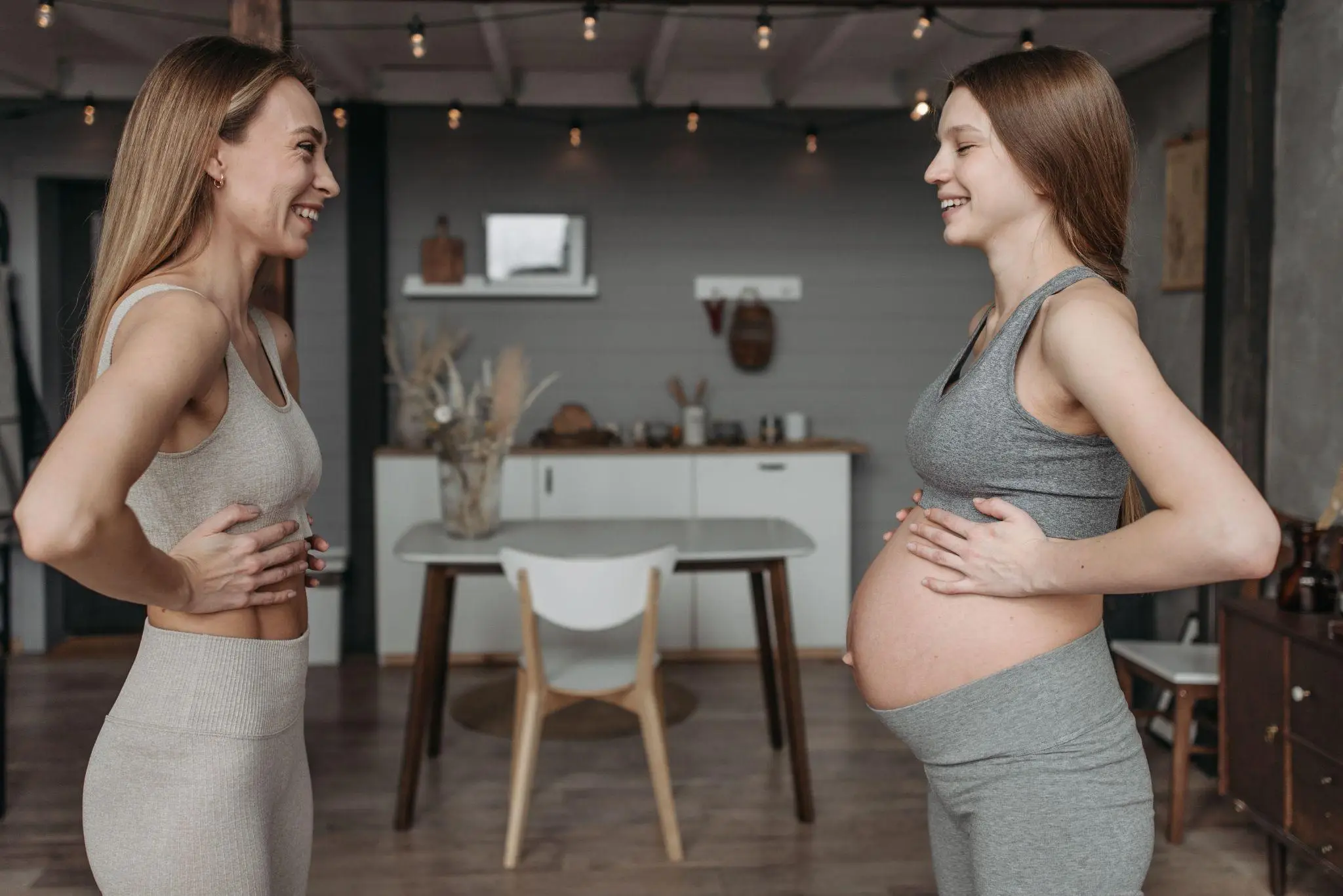 Two women in casual loungewear smiling in cozy living room setting