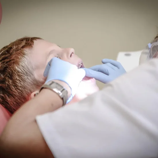 Child receiving dental check-up from dentist wearing gloves in clinic setting