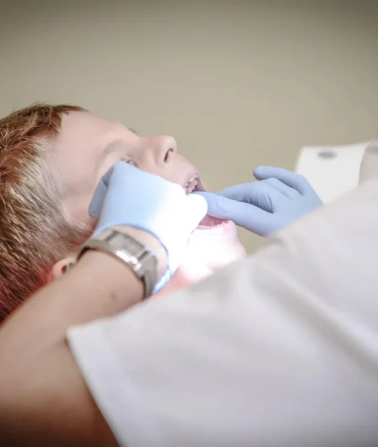Child receiving dental check-up from dentist wearing gloves in clinic setting