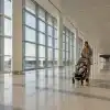 Woman pushing stroller in spacious airport terminal with large windows and natural light