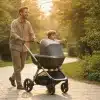 Man pushing stroller with child in sunlit park pathway surrounded by greenery