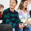Group of friends playing video games on couch indoors with game controllers