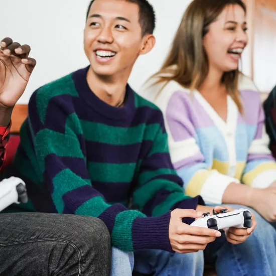 Group of friends playing video games on couch indoors with game controllers