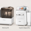 Two white bottle sterilizers with digital displays on a neutral background